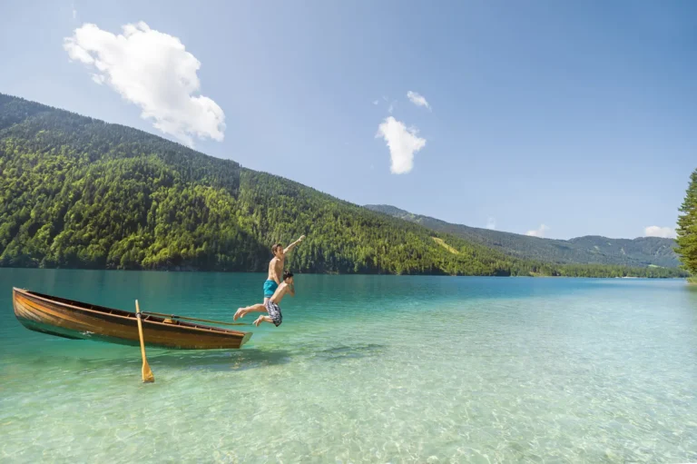 Vater und Sohn springen aus einem Ruderboot in den klaren Weissensee