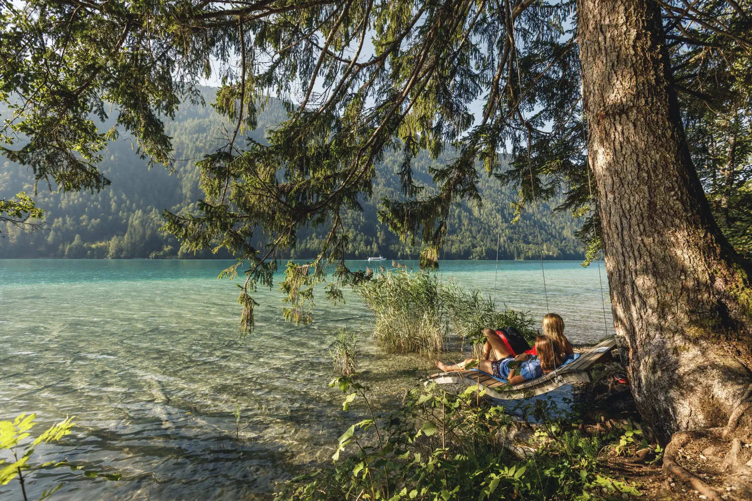 Mutter und Tochter entspannen im Hängesessel im Schatten am Weissensee